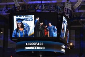 Nella in her cap and gown on the big screen at her graduation from the University of Buffalo as she accepts her Aerospace Engineering degree.